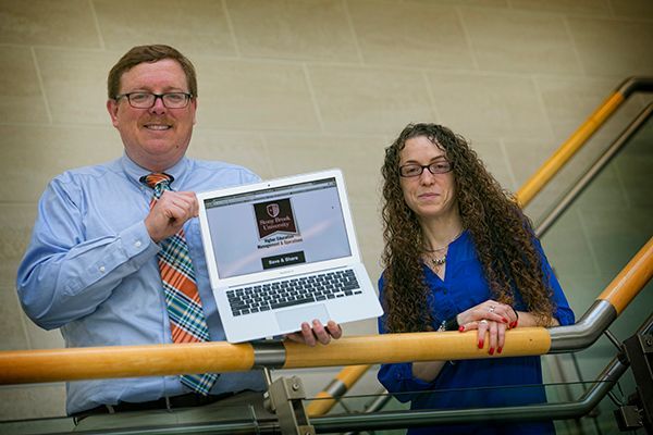 Ken Lindblom, director of the English Teacher Education Program and Amy Margolies, assistant director, with a slide of a digital badge that students in the School of Professional Development at Stony Brook University may now earn. Photo courtesy of SBU News Desk.